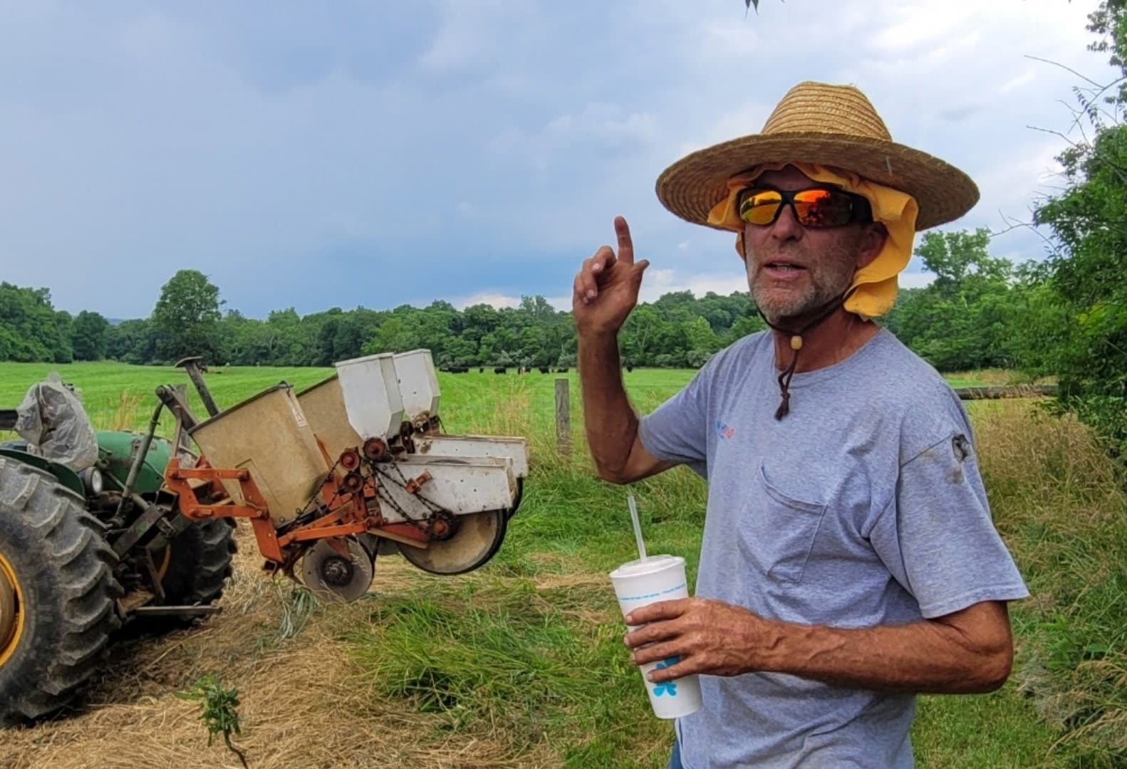 Charlie Bill McDonald standing beside a tractor and planter in a pasture at Glencoe Farm