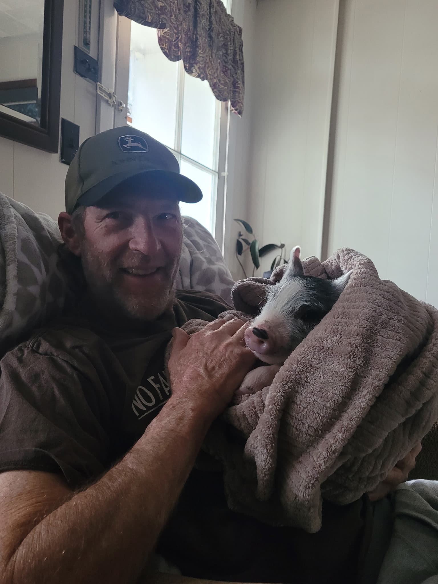 Charlie Bill holding a piglet wrapped in a blanket